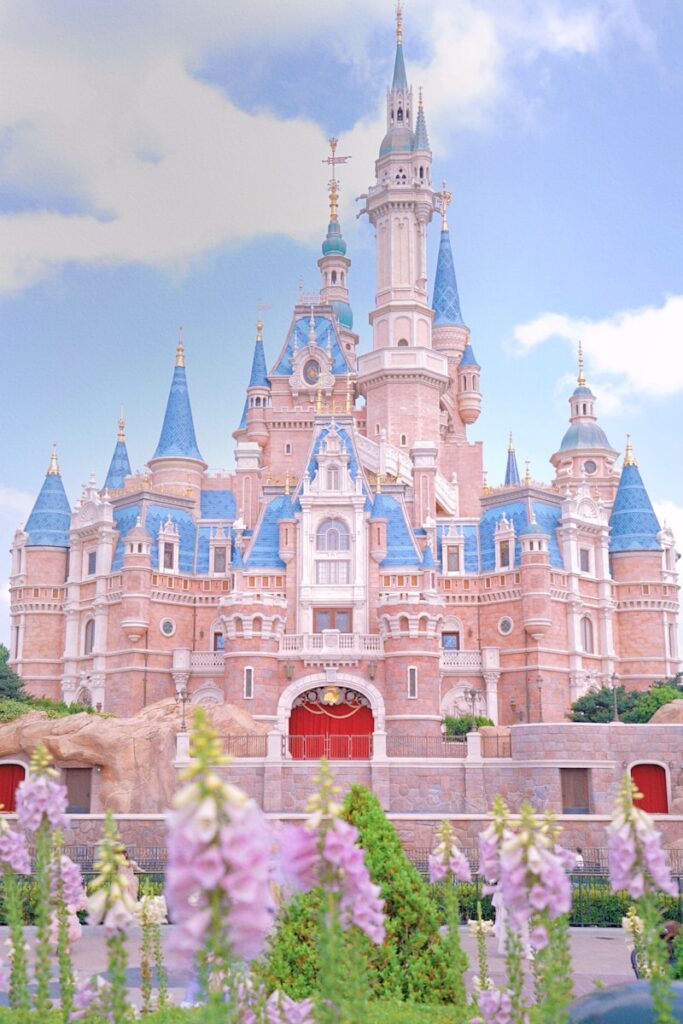 The disney castle stands tall with lovely flowers.