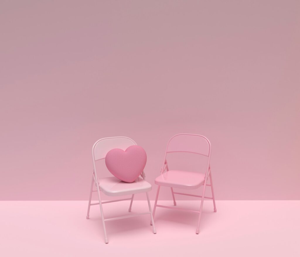 a pink chair and a white chair with a heart shaped pillow