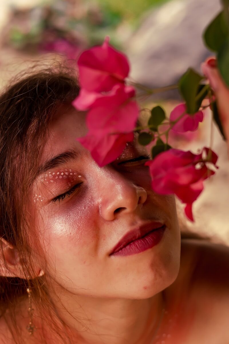 Young woman with eyes closed near pink flowers