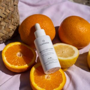 A bottle of eye cream sitting on top of a pile of oranges